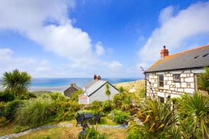 a stone house with the ocean in the background at Whitebreakers, Cottage, Garden, Sea-views, Amazing Location By Beach in Sennen