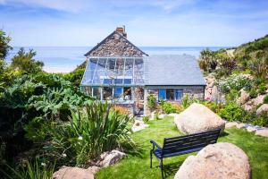 a house with a bench in front of it at Castaways, Cottage With Sea Views, Lush Gardens & Patio By the Beach in Sennen