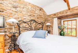 1 dormitorio con 1 cama en una pared de piedra en Petra, Cornish Cottage With lovely Garden, Wow Sea Views, By the Beach, en Sennen