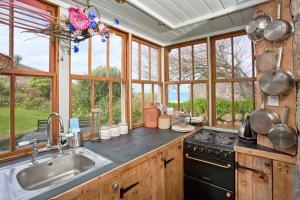 a kitchen with a stove and a sink and windows at Petra, Cornish Cottage With lovely Garden, Wow Sea Views, By the Beach in Sennen