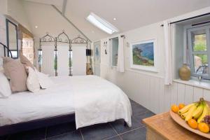 a bedroom with a bed and a bowl of fruit on a table at Basking Shark, Studio Cottage With Superb Sea Views By Beach in Sennen