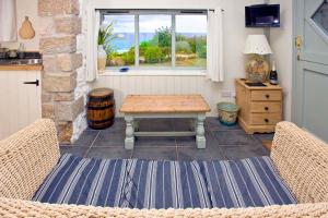 a living room with a table and a window at Basking Shark, Studio Cottage With Superb Sea Views By Beach in Sennen