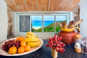 uma mesa com um prato de frutas e uma janela em Little Petra, Cottage With Garden, Superb SeaViews in Amazing Location em Sennen