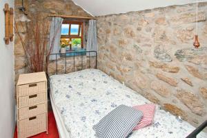 a bedroom with a bed and a stone wall at White Rose, Cornish Cottage With Sea Views & Private Garden By Beach in Sennen