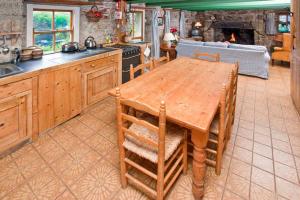 a kitchen with a wooden table with chairs and a stove at White Rose, Cornish Cottage With Sea Views & Private Garden By Beach in Sennen