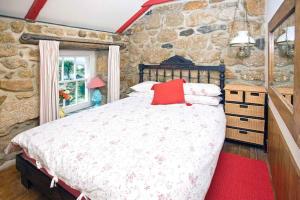 1 dormitorio con cama y pared de piedra en Penrose, Cornish Cottage With Sea Views, Garden & Patio By the Beach, en Sennen
