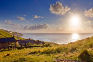 una casa en una colina junto al océano en Penrose, Cornish Cottage With Sea Views, Garden & Patio By the Beach, en Sennen