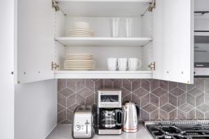 uma cozinha com armários brancos e comodidades para preparar café em 1BR in Hip E Village w Doorman Gym NYC-150 em Nova York