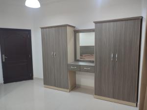 a bedroom with wooden cabinets and a desk with a mirror at رحاب السعاده rehab alsaadah apartment in Salalah