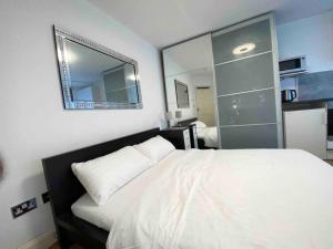 a bedroom with a white bed and a mirror at Spacious Studio 30 mins from Luton free parking in The Hyde