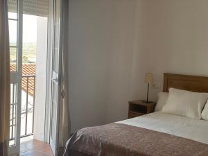 um quarto com uma cama e uma porta de vidro deslizante em El Balcón de Alange em Alange
