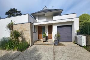 een wit huis met een garage bij Appartement Terrasse - Vue Imprenable sur le Golfe in Larmor-Baden