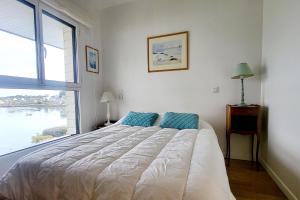 a bedroom with a large bed with a large window at Appartement Terrasse - Vue Imprenable sur le Golfe in Larmor-Baden