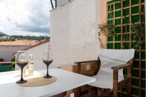 a table with two glasses of wine on a balcony at Koper House - Cozy & Tropical Oasis steps from the center in Neos Marmaras