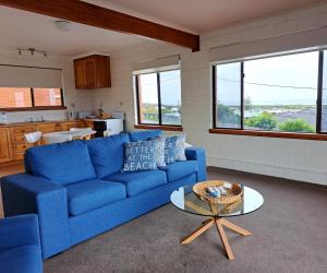 a living room with a blue couch and a table at Blue Seas Holiday Villas in Scamander