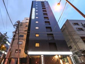 wysoki budynek z znakiem na boku w obiekcie HOTEL LiVEMAX Tokyo Kanda-Ekimae w Tokio