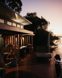 um homem sentado no convés de uma casa ao lado da água em Ark-imedes - Unique float home on the Murray River em White Sands