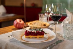 un trozo de tarta en una mesa con una copa de vino en Hotel Moserhof, en Seeboden