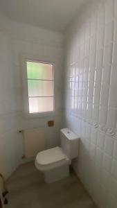 baño blanco con aseo y ventana en La Candela, en Cercedilla