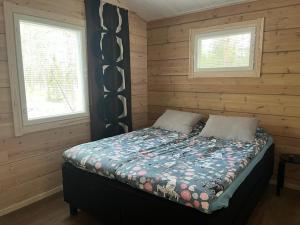 a bed in a log cabin with two windows at Holiday home Villa Esteri in Pyhätunturi