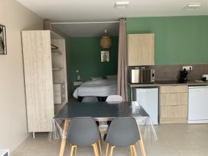 1 dormitorio y cocina con mesa y sillas. en Clos du Béron- Appartement meublé de tourisme, en Cappelle-en-Pévèle