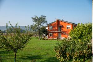 Ca' dei Berici في Tormeno: منزل برتقالي في حقل مع أشجار
