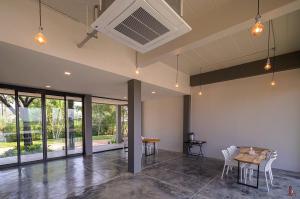 an empty room with a table and chairs and windows at BananaHill in Ban Tha Dua