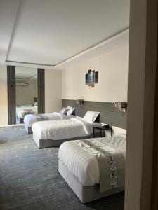 um quarto de hotel com três camas e um espelho em فيلا ساره em Al Madinah