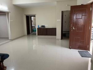 a large empty room with a door and a kitchen at SSN Home Stays in Tirupati Near Alipiri in Tirupati