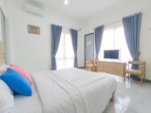 a bedroom with a white bed with blue curtains at RedDoorz at Batutulis Bogor Villa Papatong by M in Bogor
