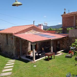 una casa de piedra con techo rojo y patio en O Enxidro en Rois