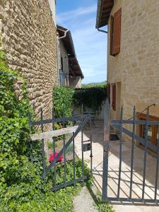 un portail en face d'un bâtiment avec une clôture dans l'établissement Le Petit Secret d'Alban, à Saint-Alban-de-Roche