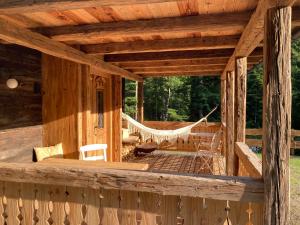 a porch of a log cabin with a hammock at Biohof Prem in Breitenbach