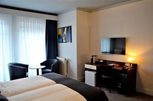 una camera d'albergo con letto, scrivania e TV di Apollo Hotel a Nijmegen
