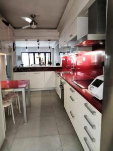 una cocina con armarios rojos y blancos y una mesa en Preciosa casa de lujo con piscina-150m de la playa en Almería