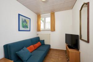 a living room with a blue couch and a tv at Gästehaus St Theresia Bodensee in Friedrichshafen