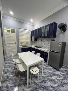 a kitchen with a white table and a refrigerator at Majestic Homestay - Pasir Puteh in Pasir Puteh
