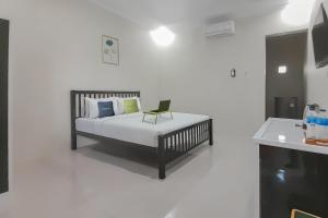a bedroom with a bed with a chair on it at Urbanview Hotel MM Indramayu by RedDoorz in Indramayu