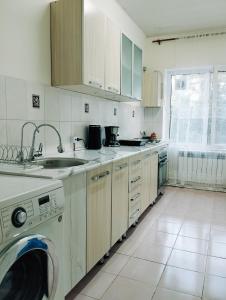 uma cozinha com um lavatório e uma máquina de lavar roupa em Salma Capsule Hostel em Bishkek