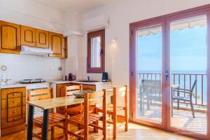 cocina con mesa y sillas y balcón en Amphitriti SeaFront Apartments, Loutra Agia Paraskevi en Agia Paraskevi