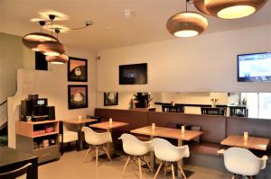 un restaurante con mesas de madera y sillas blancas en Apollo Hotel en Nijmegen