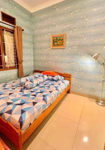 een slaapkamer met een bed met een blauwe muur bij Vila Kusuma Estate Batu in Batu