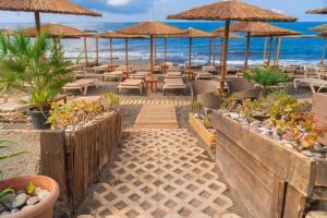イエラペトラにあるTylissos Beach Hotel - Adults Onlyのビーチ沿いのレストラン(椅子、パラソル付)