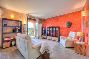 una sala de estar con paredes de color naranja y muebles blancos. en Miralago Lake View Outside Whirlpool - Happy Rentals en Ispra