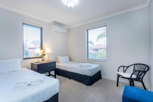 a bedroom with two beds and a chair and window at Coode Street Townhouse in Perth