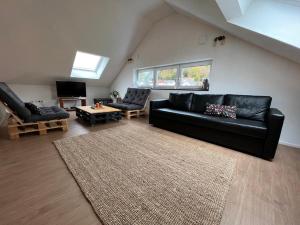 sala de estar con sofá de cuero negro y alfombra en Schwarze Eule Ferienwohnung, en Beckingen