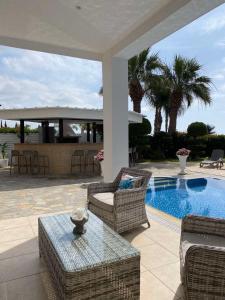 un patio con sillas, una mesa y una piscina en Ionion Beachfront Villa en Ayia Napa