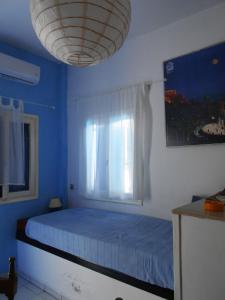 a blue bedroom with a bed and a window at Meltemia Studios in Marathokampos