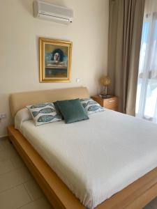 Un dormitorio con una cama blanca con una foto en la pared en Ionion Beachfront Villa, en Ayia Napa