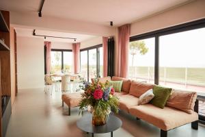 un salon avec un canapé et une table avec des fleurs dans l'établissement The Pink Penthouse, à La Panne